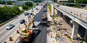 Construction workers and machinery actively repairing a major highway and bridge, showcasing infrastructure bill progress.